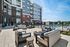 Elegant outdoor patio space with modern seating arrangement, fire pits, and a fenced swimming pool beside a contemporary residential building.