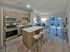 Modern open-concept kitchen with an island, stainless steel appliances, and a cozy living area featuring a sofa and dining table.