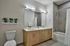 Sleek modern bathroom with double vanity, large mirror, and decorative vases, featuring a tub with shower.