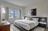 Bright modern bedroom featuring a large bed with plush pillows, elegant wall art, and a scenic window view.
