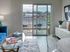 Contemporary living room with a view of a sunlit balcony, featuring a stylish glass coffee table and modern decor.