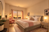 Beautifully designed bedroom featuring a plush bed, pink accent chair, modern decor, and a window with a scenic view.