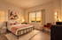A bright and modern bedroom with a stylish metal bed frame, colorful artwork, and serene window view.