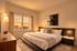 Bright modern bedroom featuring a large bed with plush pillows, elegant wall art, and a scenic window view.