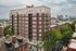 Charming brick apartment building in vibrant cityscape with tree-lined streets and panoramic skyline views.