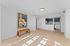 Chic and modern apartment with a sunlit open living space, stylish artwork, and a sleek kitchen featuring stainless steel appliances and elegant cabinetry.