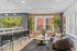 Modern and inviting lounge area with stylish bar seating, cozy curved sofa, and vibrant greenery by large windows.