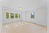 Bright, airy room with large windows overlooking lush greenery, featuring elegant light wooden flooring and minimalistic design.