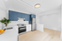 Modern kitchen with sleek blue cabinets, stainless steel appliances, and a bright open layout.