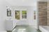 Bright and modern bathroom with elegant tiled flooring, a sleek white vanity, and large windows offering serene outdoor views.