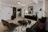 Sophisticated modern living room with sleek black furnishings and stylish contemporary art, leading to a chic kitchen with geometric tile flooring.