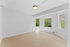 Bright, airy room featuring large windows with sunny views and sleek hardwood floors, perfect for modern living.