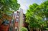 Vibrant apartment building with brick facade and lush green trees, ideal for serene living.