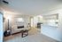 Cozy living space with elegant decor, white sofa, modern coffee table, and inviting kitchen bar area.