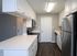 Modern kitchen with sleek white cabinetry, stainless steel appliances, and elegant wood flooring.
