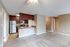 Modern apartment interior showcasing an open-concept kitchen with elegant cabinetry, sleek stainless steel appliances, and a spacious living area with soft carpet and neutral tones.