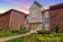 Charming brick apartment building with lush greenery, featuring a welcoming front entrance and large windows at sunset.