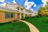 Charming and inviting apartment complex with brick and siding exterior, surrounded by lush green landscape and a well-maintained pathway.