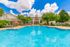 Inviting outdoor pool area with crystal-clear water, surrounded by lush greenery and sun loungers, perfect for relaxation.