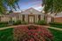 Charming leasing center with classic architecture and vibrant garden under a colorful sunset sky.