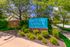 Charming entrance sign for Brittany Springs luxury apartments, surrounded by lush greenery and a sunny pathway.