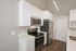 Contemporary kitchen with sleek stainless steel appliances, elegant white cabinetry, and stylish wood flooring.