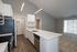Modern kitchen with sleek stainless steel appliances, elegant countertops, and open floor plan leading to a bright living area with large sliding windows.