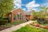 Charming brick-front leasing center surrounded by lush greenery and vibrant flowers under a sunny sky at The Green at Chevy Chase.