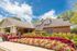 Charming brick building with lush, colorful landscaping under a bright blue sky, offering a welcoming atmosphere.