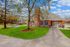 Charming brick apartment with large windows surrounded by lush green landscape and serene pond view.