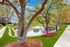 Serene view of a beautifully landscaped garden with lush green grass, mature trees, and a tranquil pond with a charming fountain.
