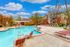 Inviting apartment complex pool area with vibrant loungers and umbrellas, surrounded by lush greenery and pristine facilities.