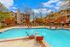 Inviting apartment complex featuring a sparkling swimming pool surrounded by comfortable lounge chairs and lush landscaping, perfect for relaxation and leisure.
