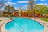 Inviting outdoor pool with sun loungers set against a backdrop of modern apartments and lush trees, perfect for relaxation.