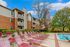 Charming apartment complex with spacious balconies, surrounded by lush greenery and a refreshing outdoor pool, perfect for relaxation.