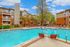 Inviting apartment complex showcasing a sparkling outdoor pool surrounded by comfortable lounge chairs and vibrant trees, perfect for relaxation and enjoyment.