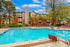 Inviting apartment complex with a sparkling swimming pool, surrounded by lush greenery and comfortable lounge chairs, perfect for relaxation and leisure.