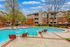 Inviting apartment complex with a shimmering pool, surrounded by stylish lounge chairs and lush trees, perfect for relaxation and leisure.