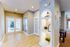 Inviting hallway with elegant French doors, featuring stylish recessed lighting and decorative shelving, leading to a bright, airy living space.