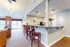 Inviting open-plan living area with a cozy fireplace, elegant pendant lighting, and a stylish kitchen bar with wooden chairs.