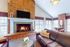 Inviting living room with a cozy fireplace, elegant brick accents, and natural light streaming through large windows.