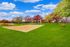 Scenic outdoor sand volleyball court set amidst lush greenery and vibrant trees under a clear blue sky.