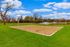 Inviting outdoor sand volleyball court set in a lush green park with serene pond views and vibrant fountains.