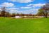 Tranquil park landscape featuring a serene pond with charming fountains, surrounded by lush greenery and vibrant trees.