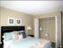 Inviting bedroom with elegant decor, featuring a cozy bed adorned with colorful pillows, wall art, and a spacious closet with open shelving.