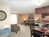 Bright and inviting living room with modern d&eacute;cor, cozy seating area, and open kitchen with dining table.