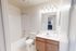 Modern, bright bathroom with sleek fixtures, featuring a full bathtub, elegant vanity with wood cabinetry, and ample lighting for a refreshing experience.