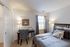 Bright and cozy bedroom with plush bedding, a stylish desk area, and ample natural light from a large window.