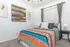 Bright and inviting bedroom with vibrant striped bedding, elegant wall art, and sleek modern lamps, offering a cozy and stylish retreat.