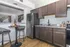 Modern kitchen with sleek dark cabinets, stainless steel appliances, and a granite countertop, featuring a cozy breakfast nook with stylish seating.